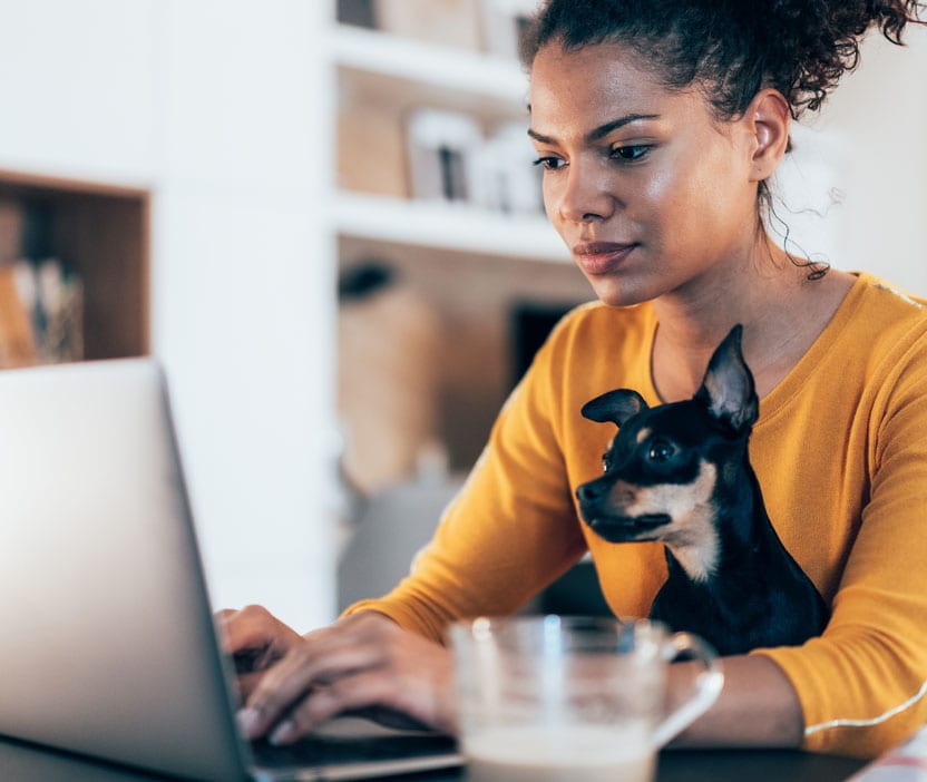 A woman working from home securely with her dog by her side using a VPN for Mac.