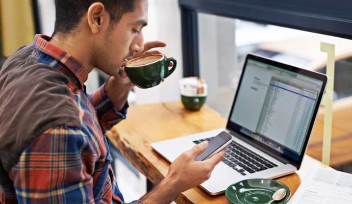 woman on couch looking at cell phone launching Norton 360 with AntiVirus Plus.